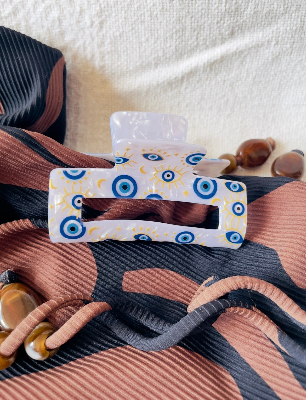 hair clip with blue and white evil eye pattern on a textured fabric background