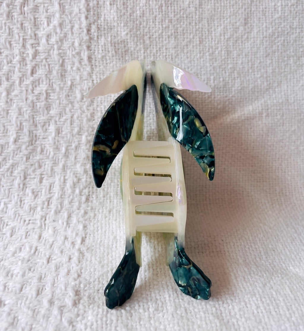 Decorative hair clip shaped like a turtle on a textured white background